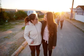 A woman and a girl walking together, each with an arm around the other.