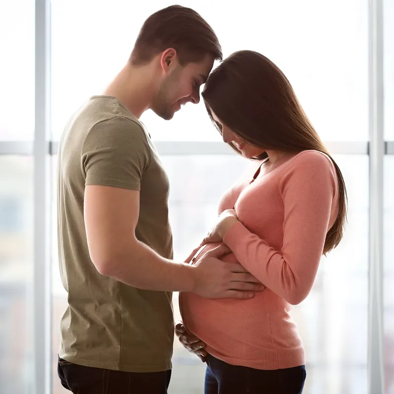 A young pregnant couple hug each other