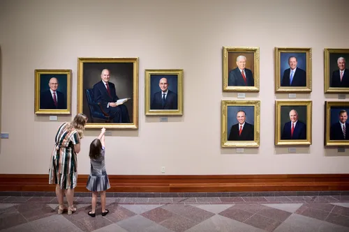 आमा र छोरी सम्मेलन केन्द्रमा चर्च अध्यक्षहरूको चित्र हेर्दै