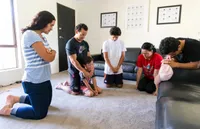 A couple and their children kneel in family prayer