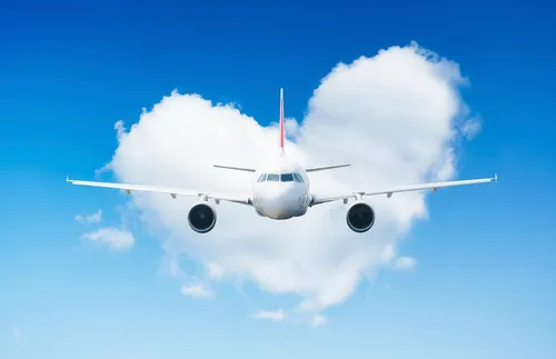 an airplane flying in front of heart-shaped cloud
