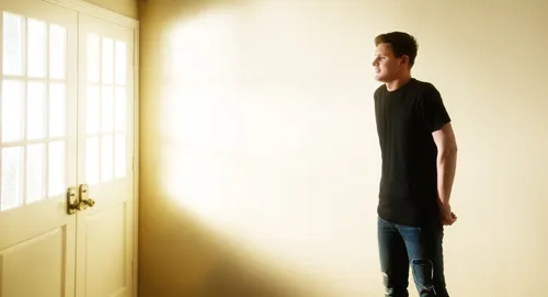 young adult man looking out window