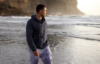 A man walks alone on a beach looking out to sea