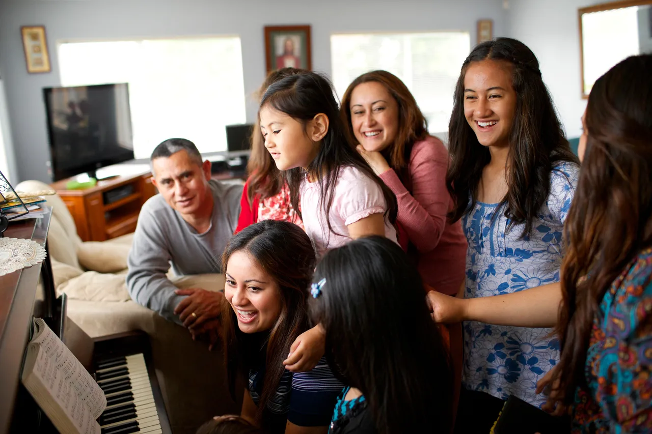A large family gathers around the piano