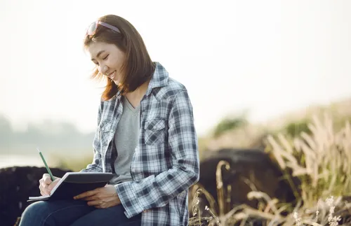 young adult woman writing in a journal