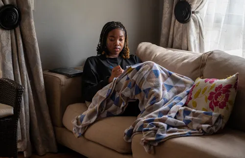 a young adult woman sitting on the couch and writing in a notebook