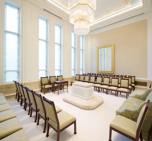 Interior image of the Bangkok Thailand Temple showing a Sealing Room. The image features chairs along the sides of the room with an altar in the middle. Stained glass windows feature in the image as well.