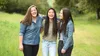 three young adult women friends embracing and laughing