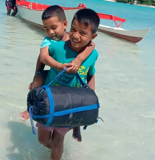 Boy holding another boy on his back in the ocean