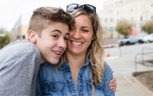 a young man gives his mom a hug while they are outside