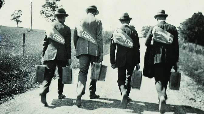 View of four Eastern States missionaries walking down country road carrying suitcases and wearing Cumorah banners on their backs as part of Book of Mormon Centennial celebration

Inscribed on verso "From Hugo B. Ensign . . . Chester, Pa. This was taken on the march to Palmyra, Sept. 17, 1923."