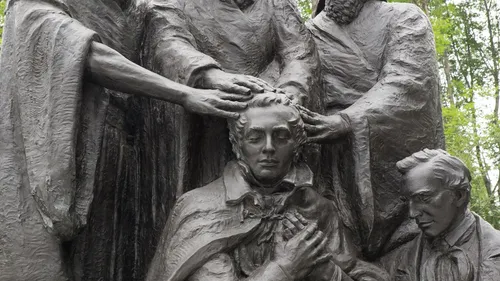 Close-up photo of a sculpture depicting Peter, James, and John conferring the Melchizedek Priesthood on Joseph Smith.