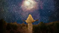 Photographic illustration of the pre-mortal Jesus Christ (seen from the back) wearing a white robe.   He has His arms extended as he looks at a darkened expanse of space filled with stars.