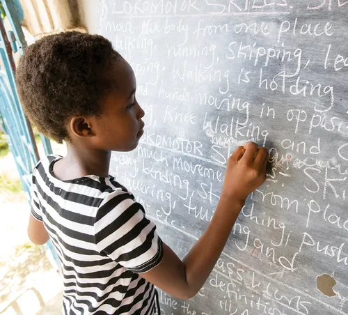 child writing on chalkboard