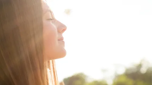 young woman with sun shining on her face