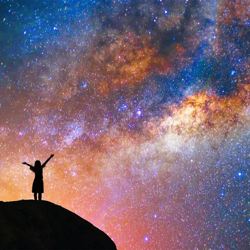 girl with outstretched arms looks at stars in sky