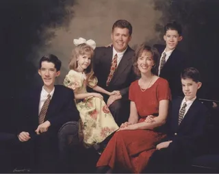 Formal portrait of a family with four children.