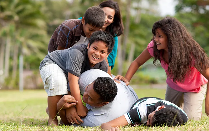 A family play football together in a park living the word of wisdom