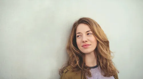 Young adult woman leaning against a wall