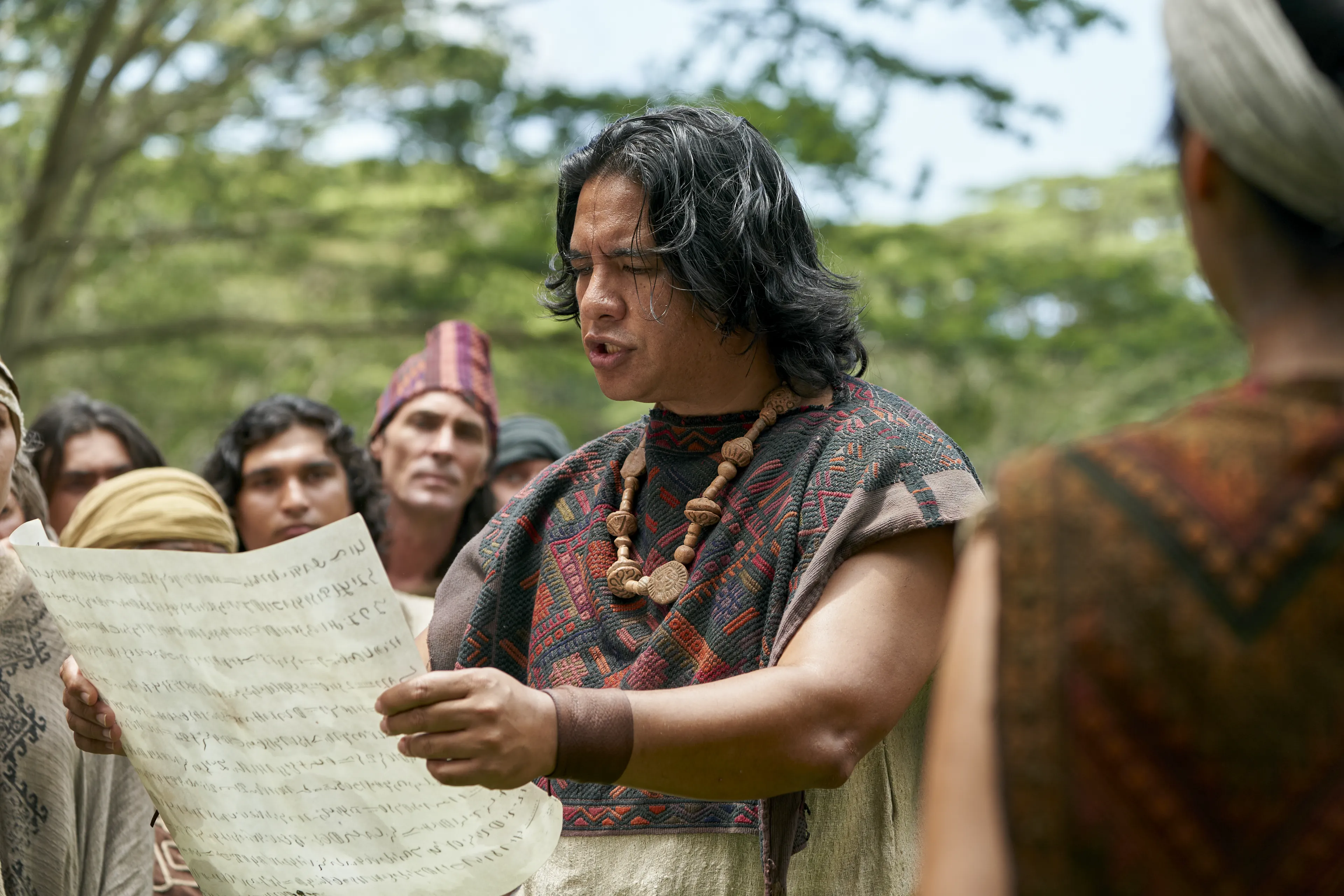 Men and women gather to listen to the teaching of King Benjamin as they are read from a parchment in the Land of Zarahemla.