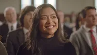 A woman smiling enjoys learning about the gospel of Jesus Christ during a Sunday meeting