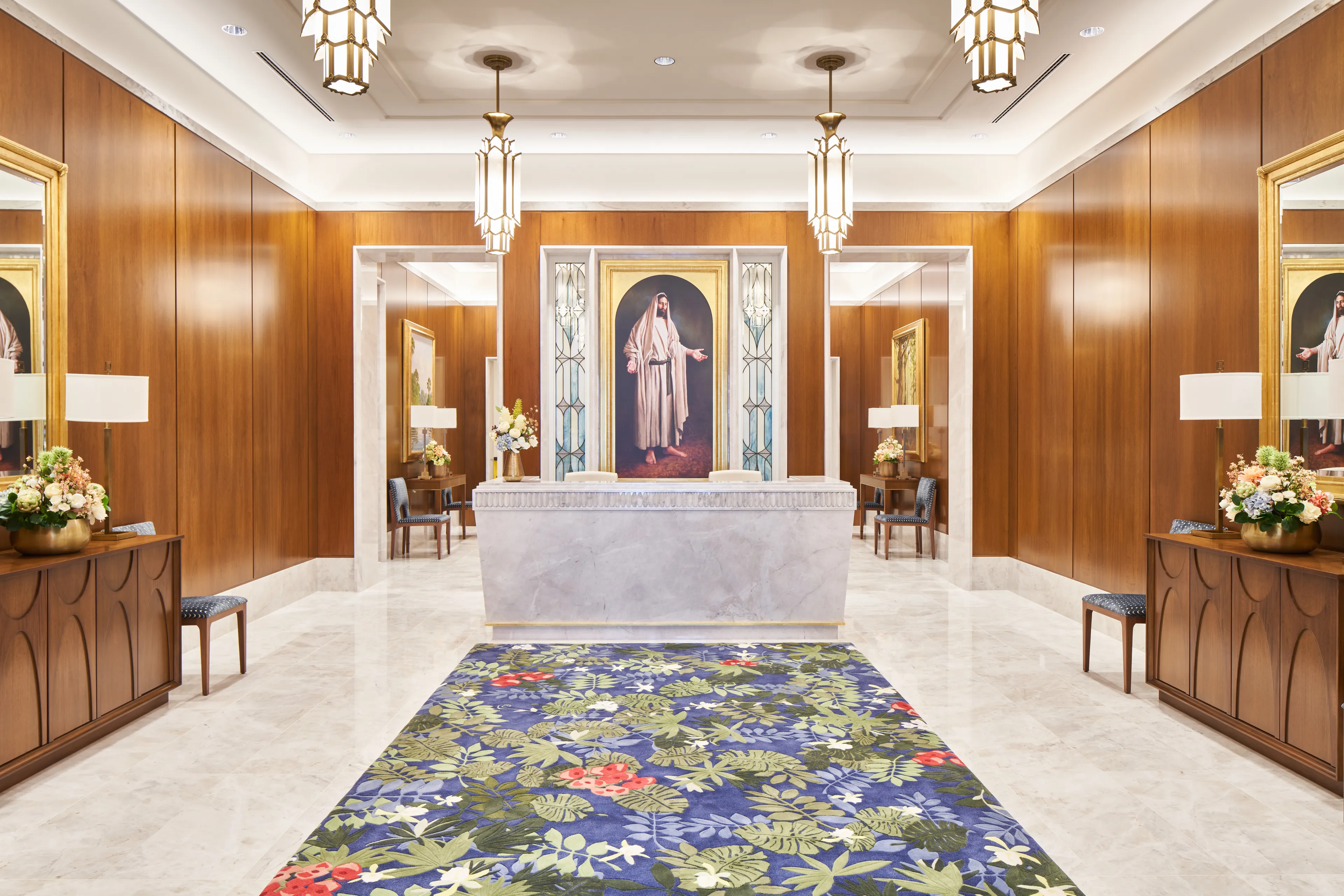 Interior image of the Brasilia Brazil Temple Recommend desk. There is stained glass art of the Savior behind the desk.  © undefined ipCode 1.