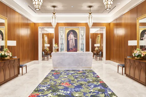 Interior image of the Brasilia Brazil Temple Recommend desk. There is stained glass art of the Savior behind the desk. 