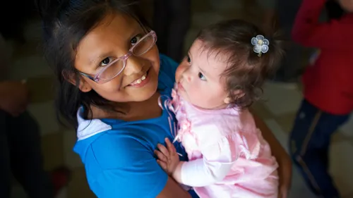 a girl holding a baby