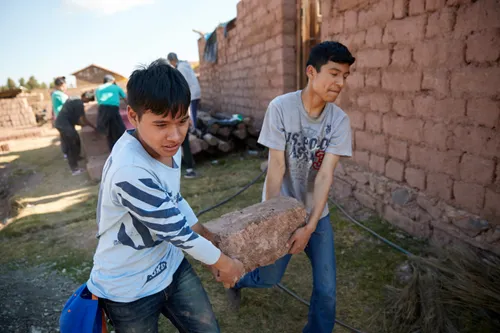 young men lifting heavy rocks and bricks