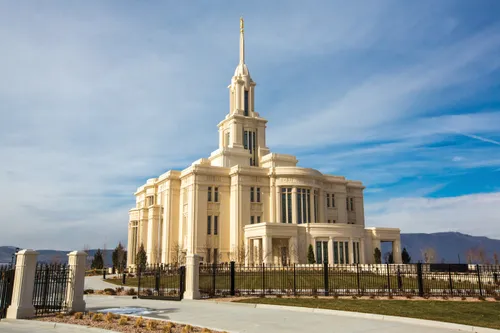 A view of the east side of the Payson Utah Temple during sunrise, including scenery and a clear sky.