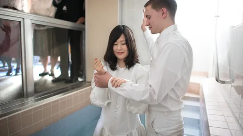 a man baptizing a woman in a baptismal font