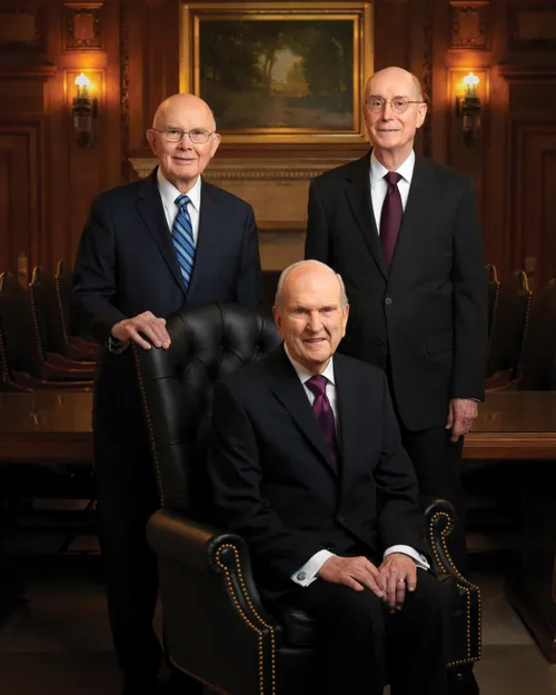 Un retrato de la Primera Presidencia, con el presidente Russell M. Nelson sentado en una silla y el presidente Dallin H. Oaks y el presidente Henry B. Eyring de pie detrás de él.