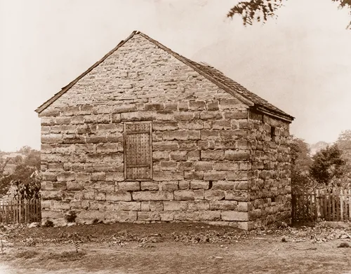 Black-and-white photo of a small, crude brick building