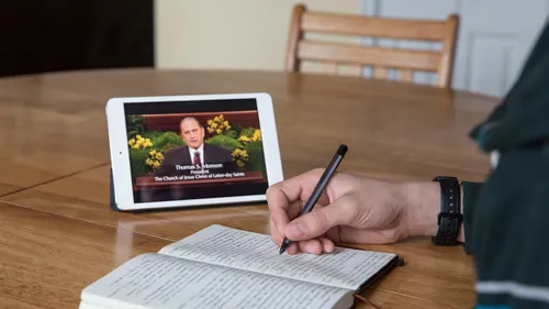 someone taking notes while watching general conference on a tablet