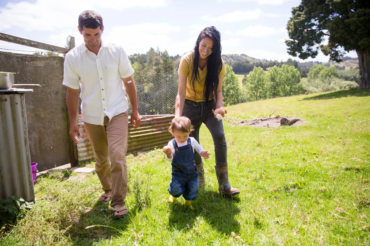 A couple with their toddler walking around a rulal homestead