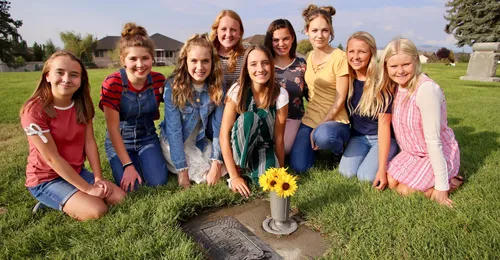 girls at grave with sunflowers