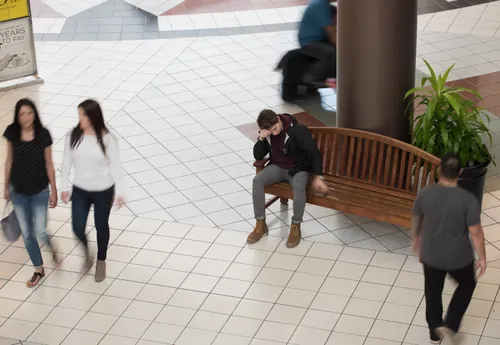 young man sitting on a bench in a mall