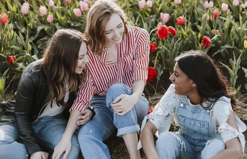 friends sitting near a field of flowers