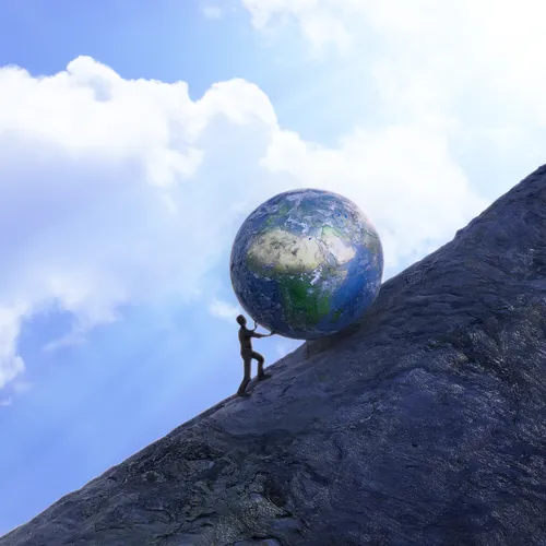 person pushing a large globe up a hill