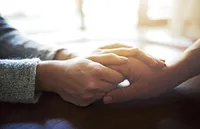 A woman holds a mans hands