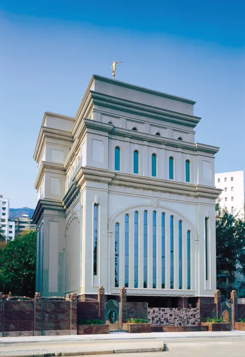 A view of the front of the Hong Kong China Temple from across the street in the daytime, with a clear blue sky overhead.