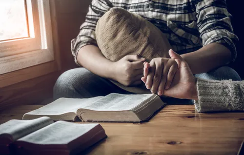 two hands clasped by scriptures