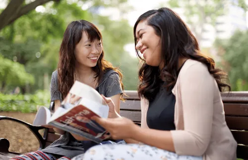 two women sitting on a park bench