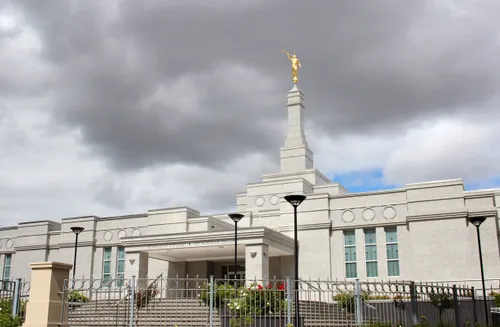 The Perth Australia Temple behind a fence, with gray clouds overhead.