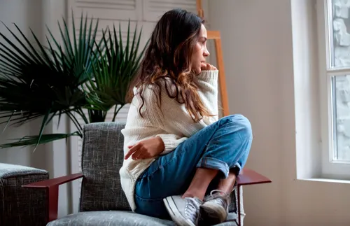 woman sitting on a chair and staring out the window