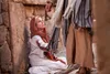 woman sitting on the floor touching jesus clothes as he walks by