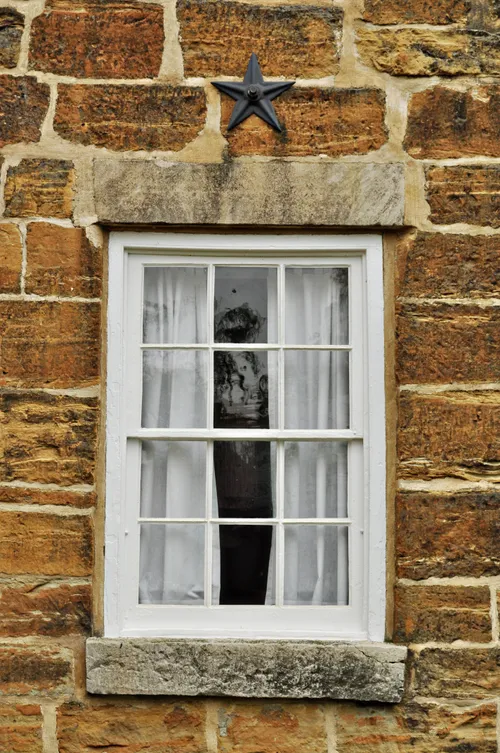 A white-framed window with a metal star above it on the side of Carthage Jail.