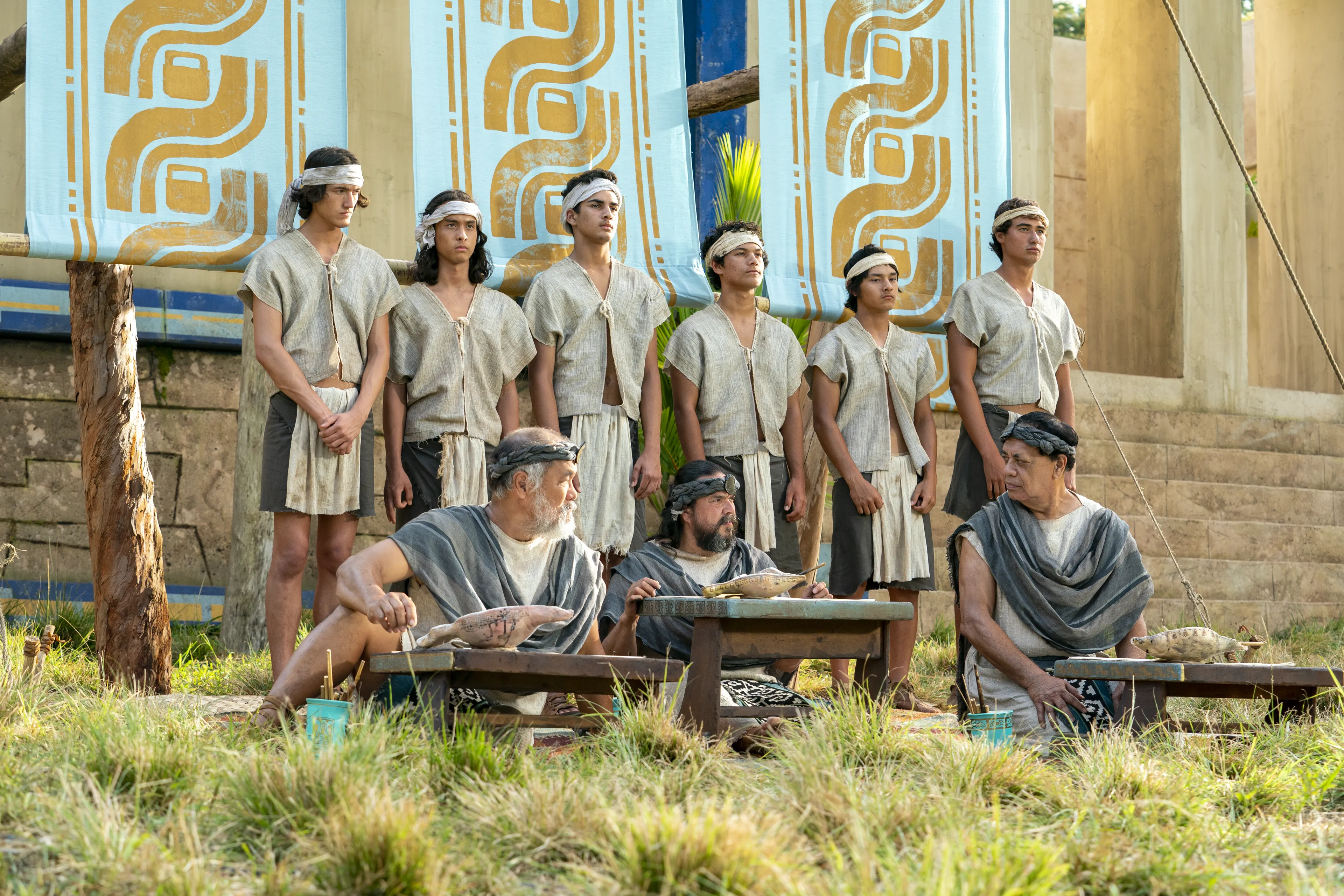 Scribes sit, taking notes on parchment of what King Benjamin is teaching in the Land of Zarahemla. Behind them, runners stand ready to take the teachings to the Nephite people.
