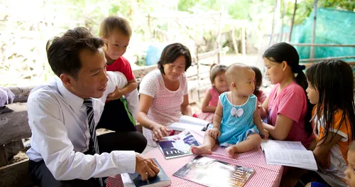 Family in Sunday attire sitting around a table with Church magazines.