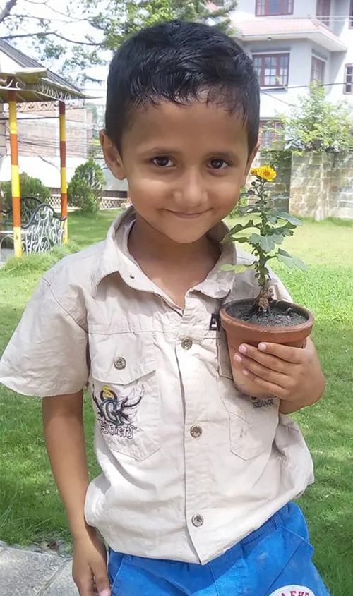 Photo of smiling boy holding potted plant